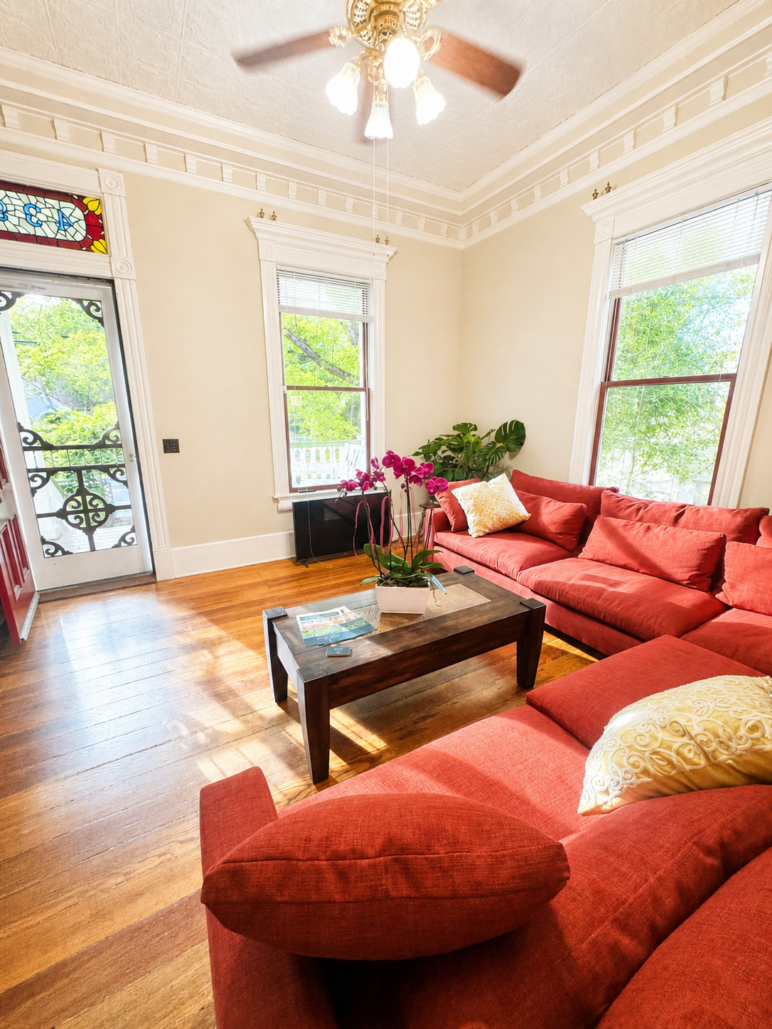 Living room with sectional sofa, ceiling fan, and stained glass door